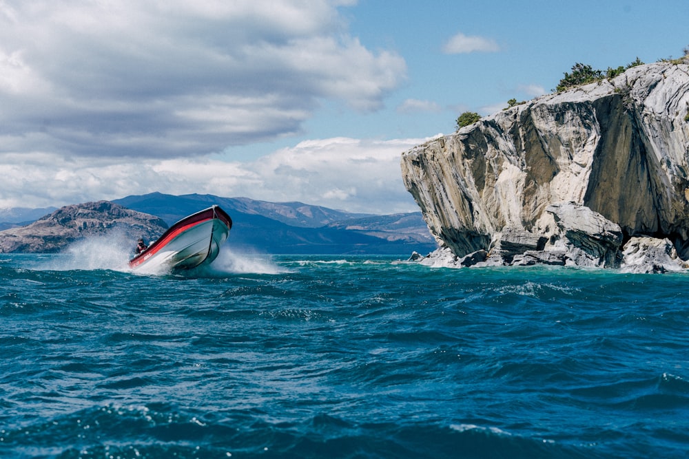 Un bateau est dans l’eau près d’une formation rocheuse