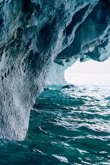 a large rock sticking out of the side of a body of water