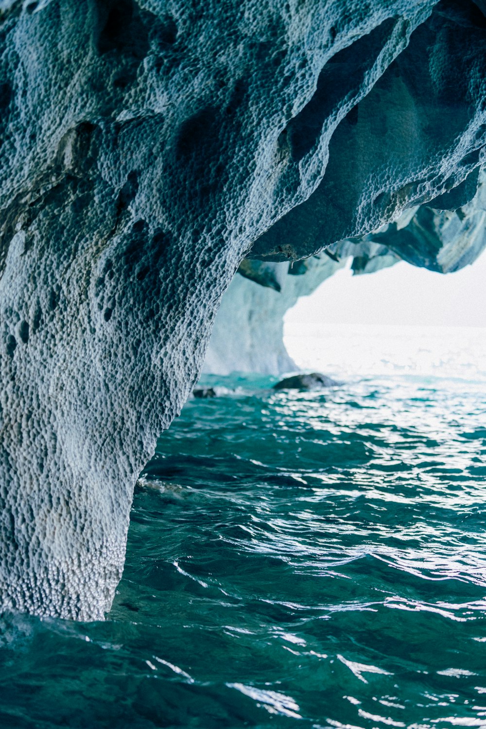 a large rock sticking out of the side of a body of water