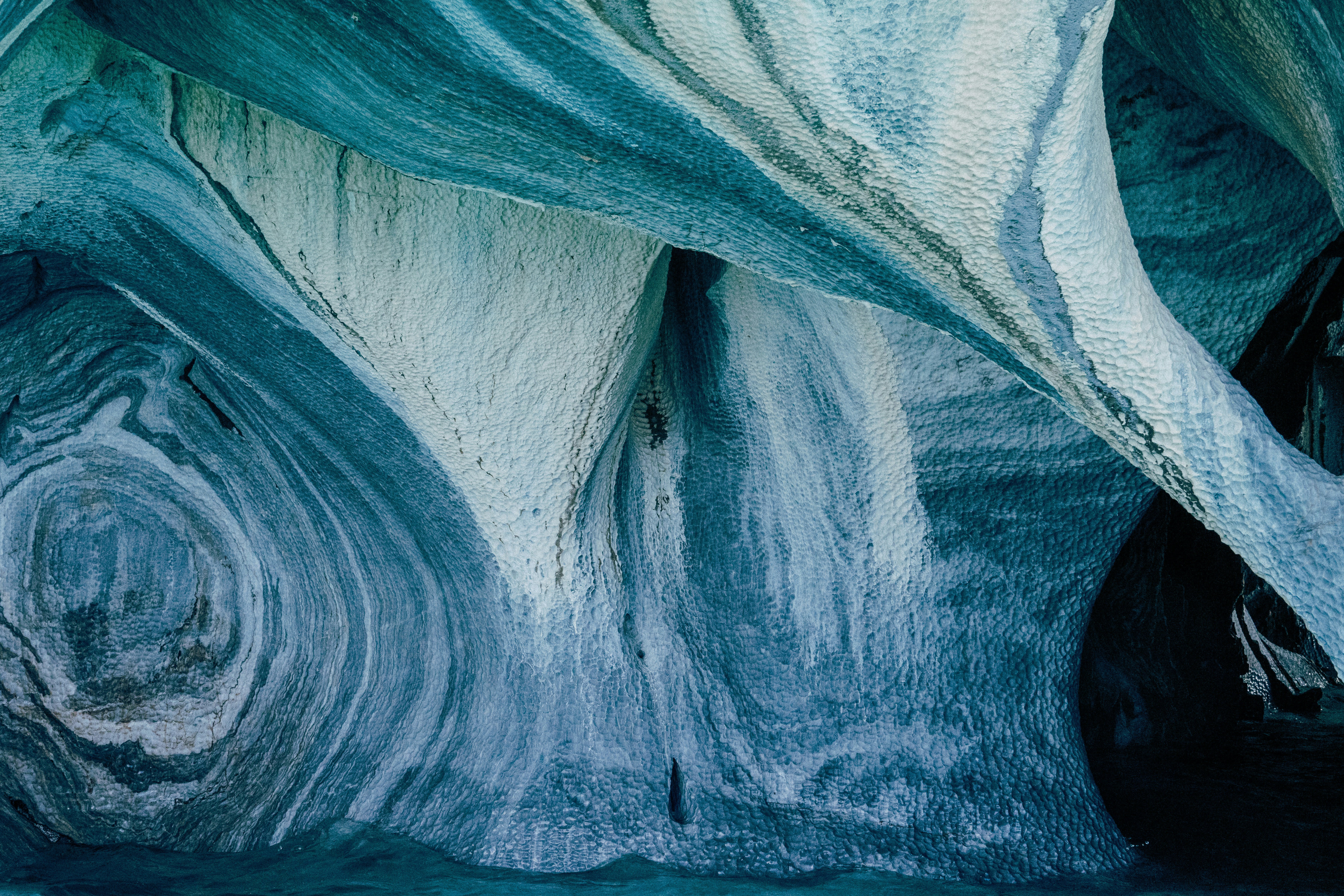 a blue and white ice cave with water flowing down it, 