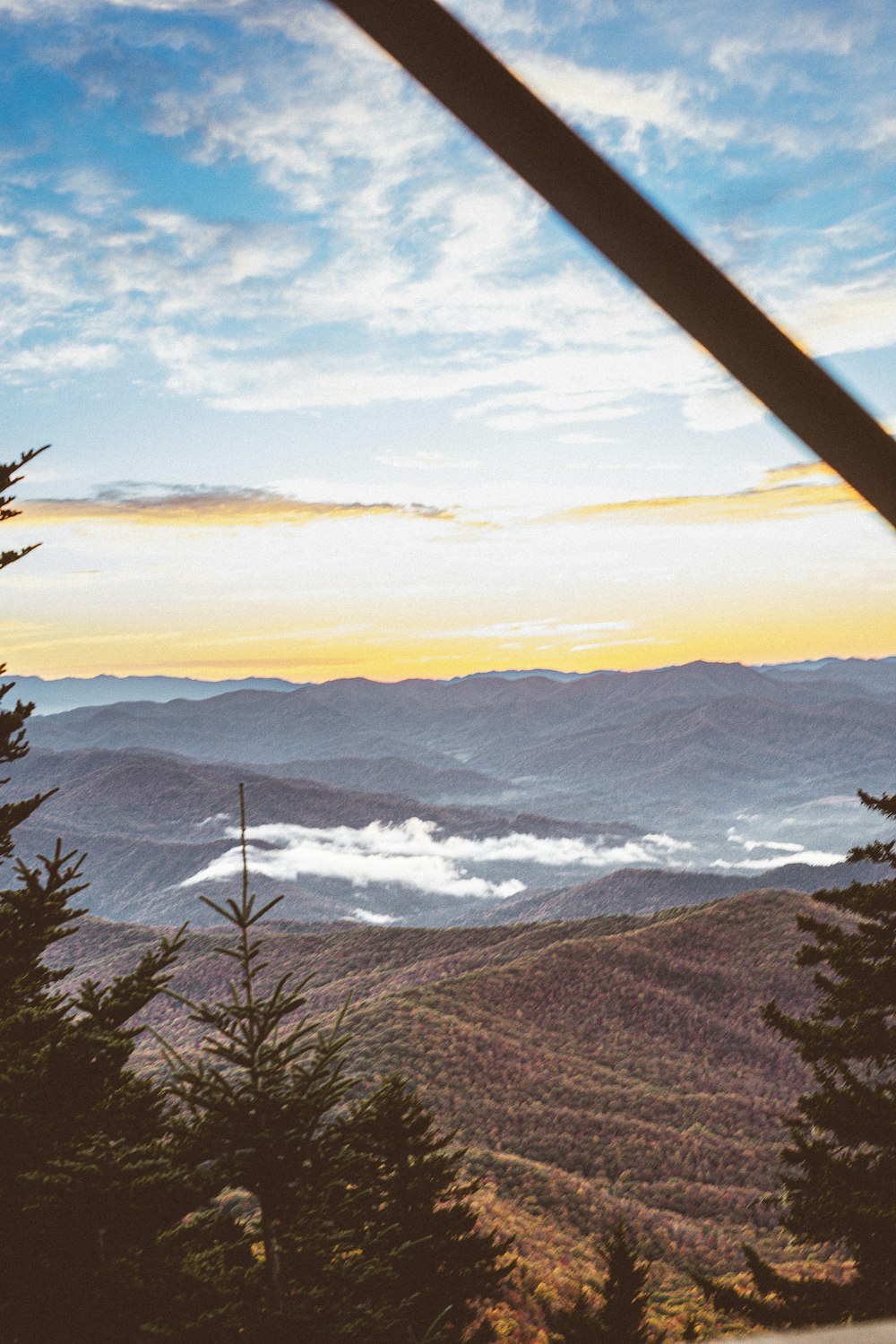 a view of the mountains and clouds from the top of a hill