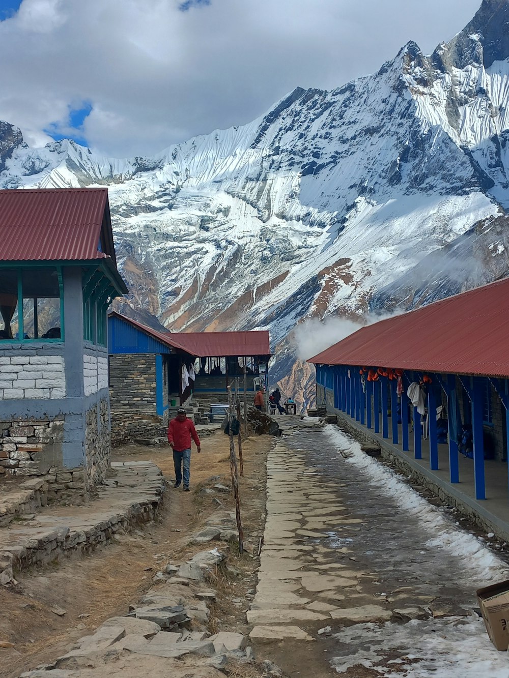 a man walking down a dirt road next to a mountain