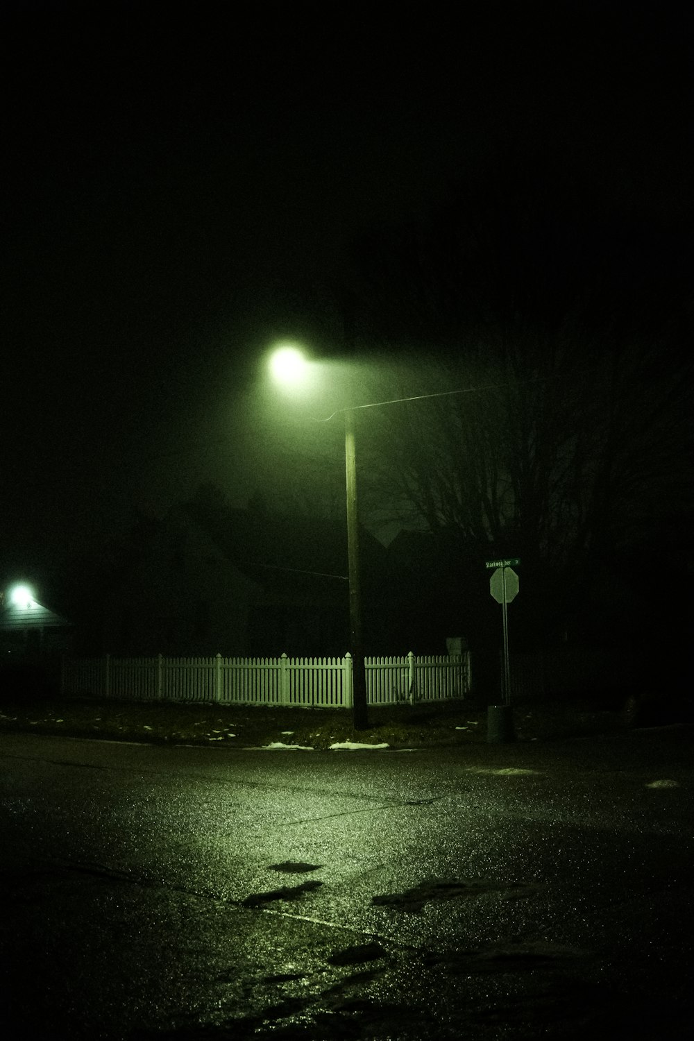 une rue sombre la nuit avec un lampadaire