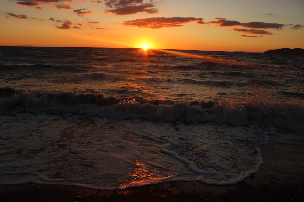 the sun is setting over the ocean with waves