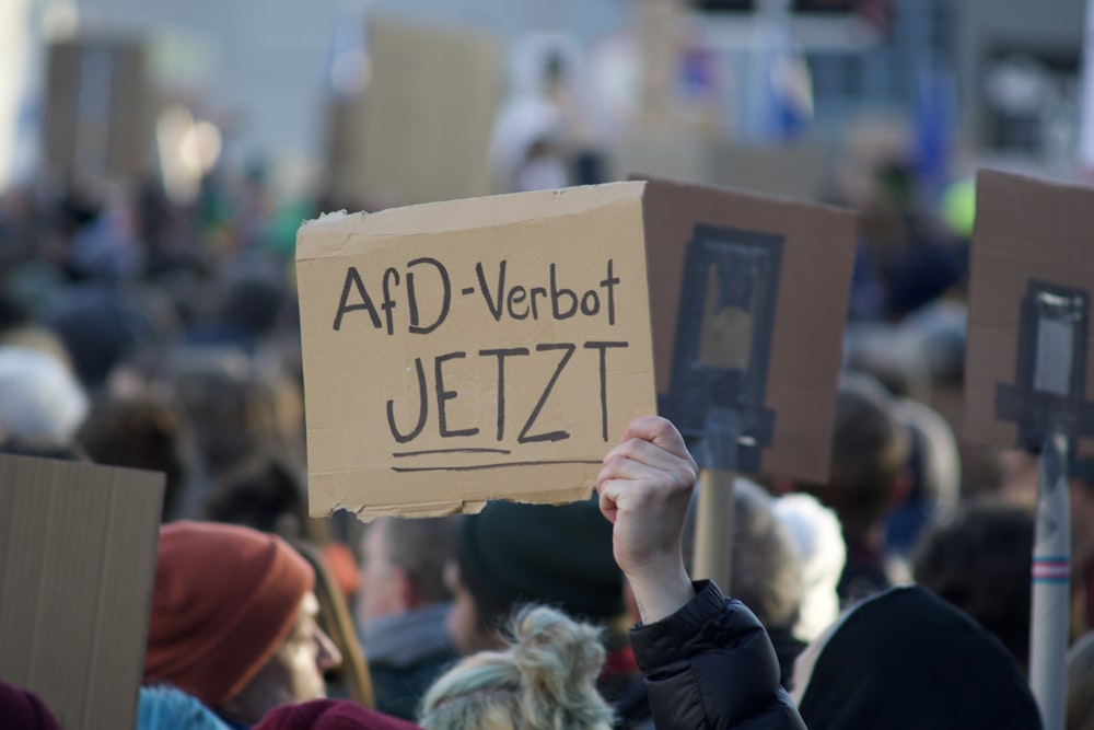 a person holding a cardboard sign in front of a crowd