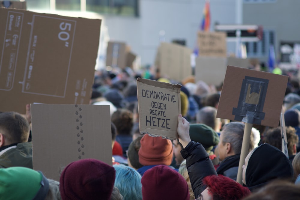 eine Menschenmenge, die Schilder vor einem Gebäude hochhält