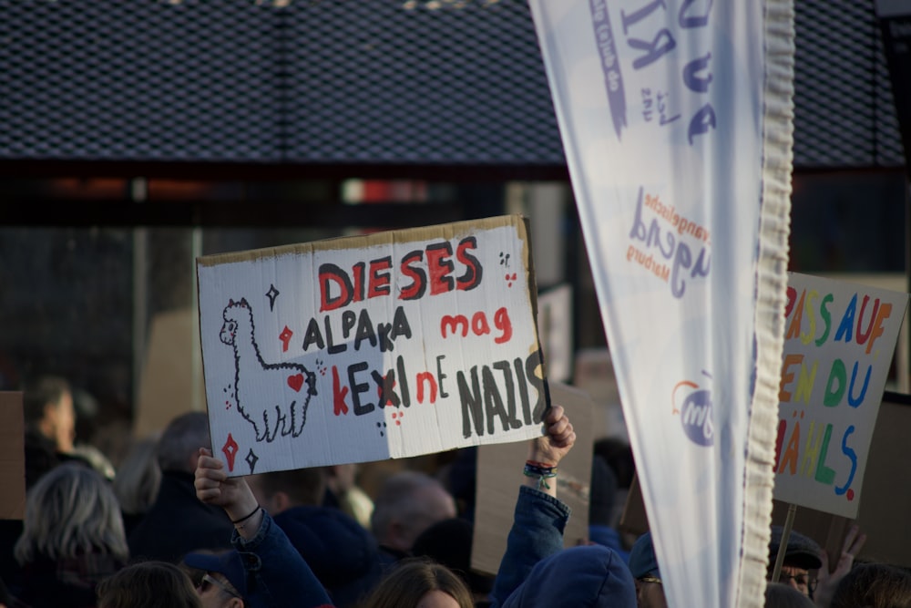 a group of people holding up signs in front of a building