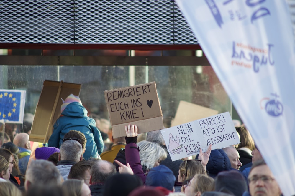 a crowd of people holding signs in front of a building