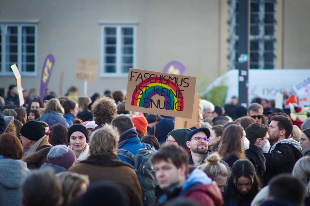 a crowd of people standing around each other holding signs