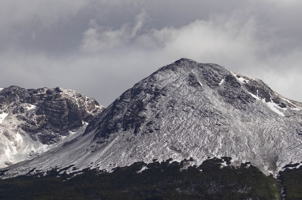 a mountain covered in snow under a cloudy sky