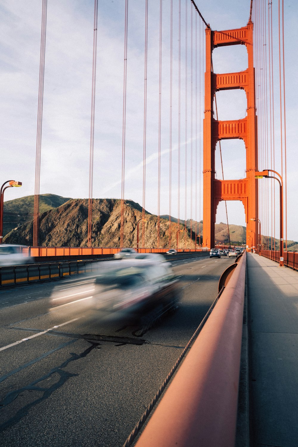 a car driving over a bridge with a mountain in the background