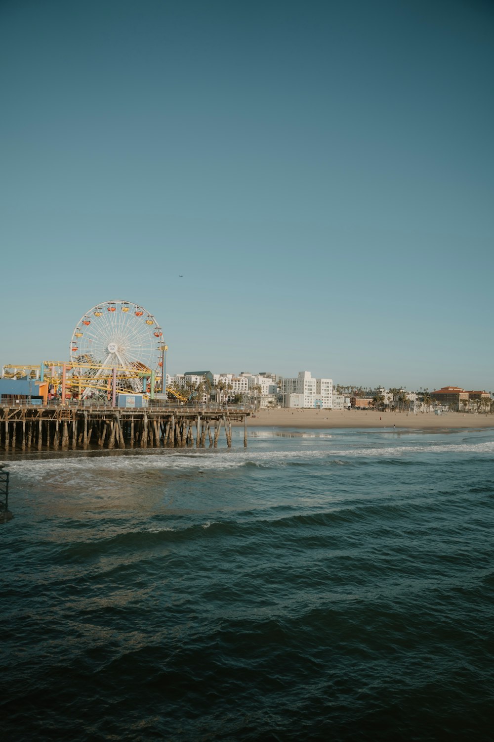 a ferris wheel sitting on top of a pier next to the ocean