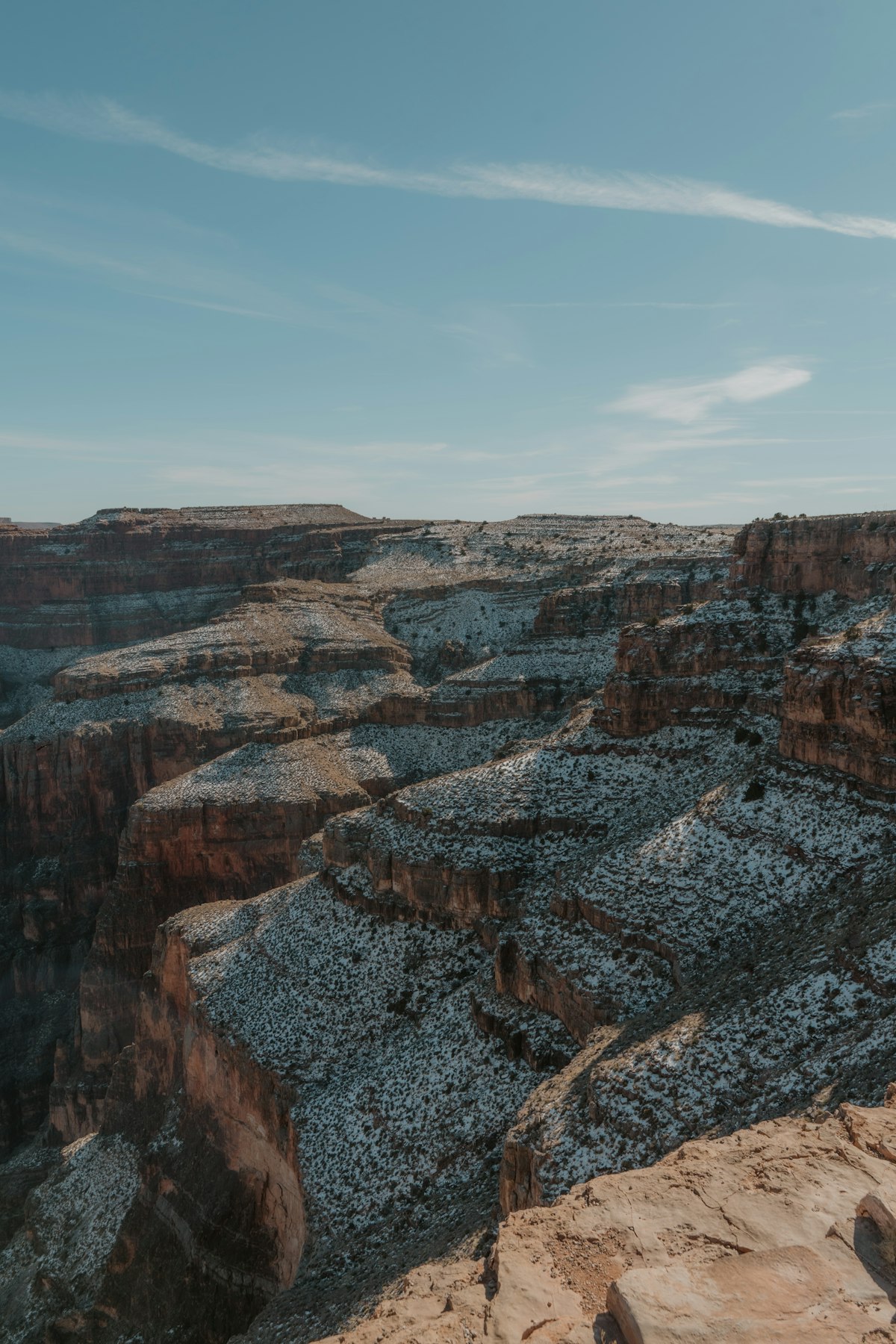Lone figure on a cliff edge dwarfed by the vast Grand Canyon.
