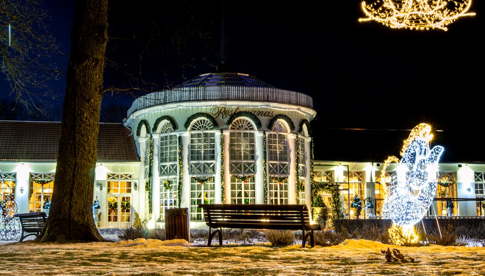 a park bench sitting in front of a building covered in christmas lights