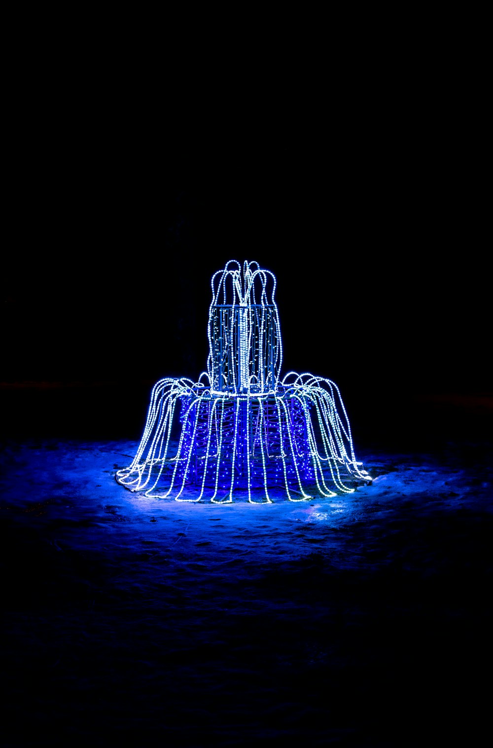 a water fountain is lit up in the dark