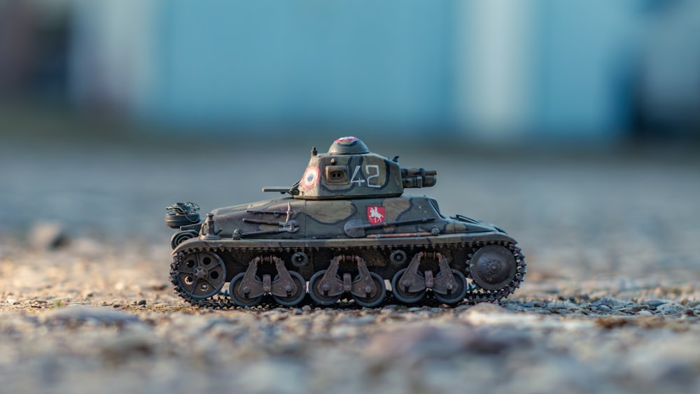 a toy tank sitting on top of a sandy ground