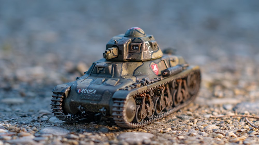 a toy tank sitting on top of a gravel field