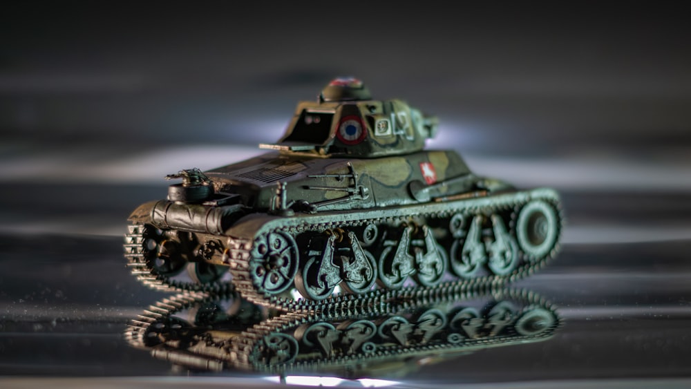 a toy tank is sitting on a reflective surface