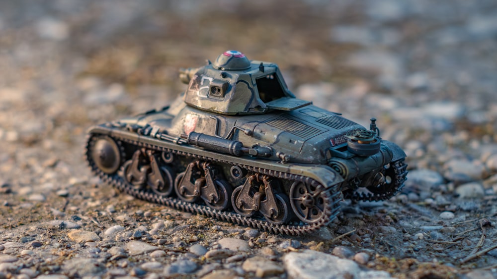 a toy tank sitting on top of a rocky ground