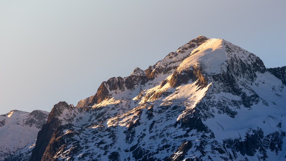 a large mountain covered in snow under a blue sky