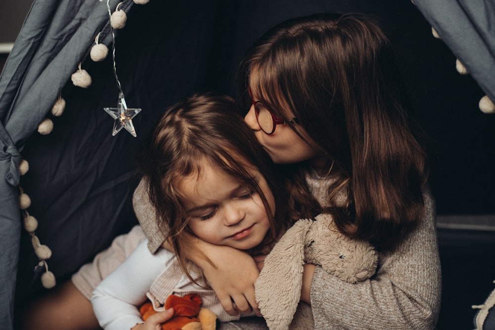 two little girls hugging each other in a tent