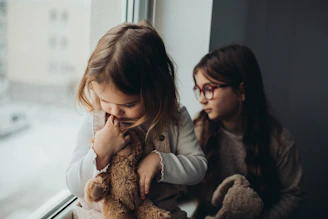 two young girls sitting next to each other on a window sill