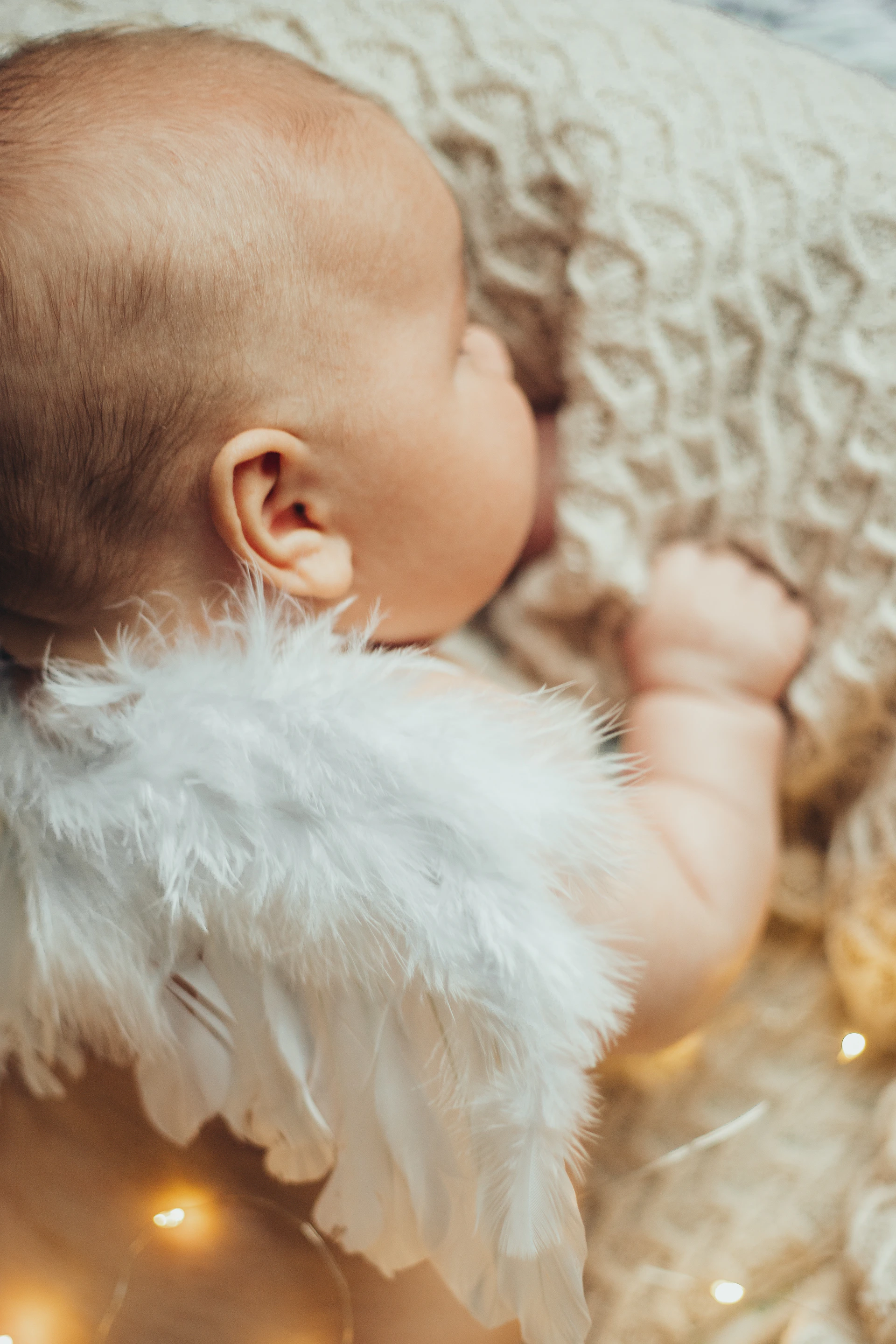 a baby wrapped in a blanket with white feathers