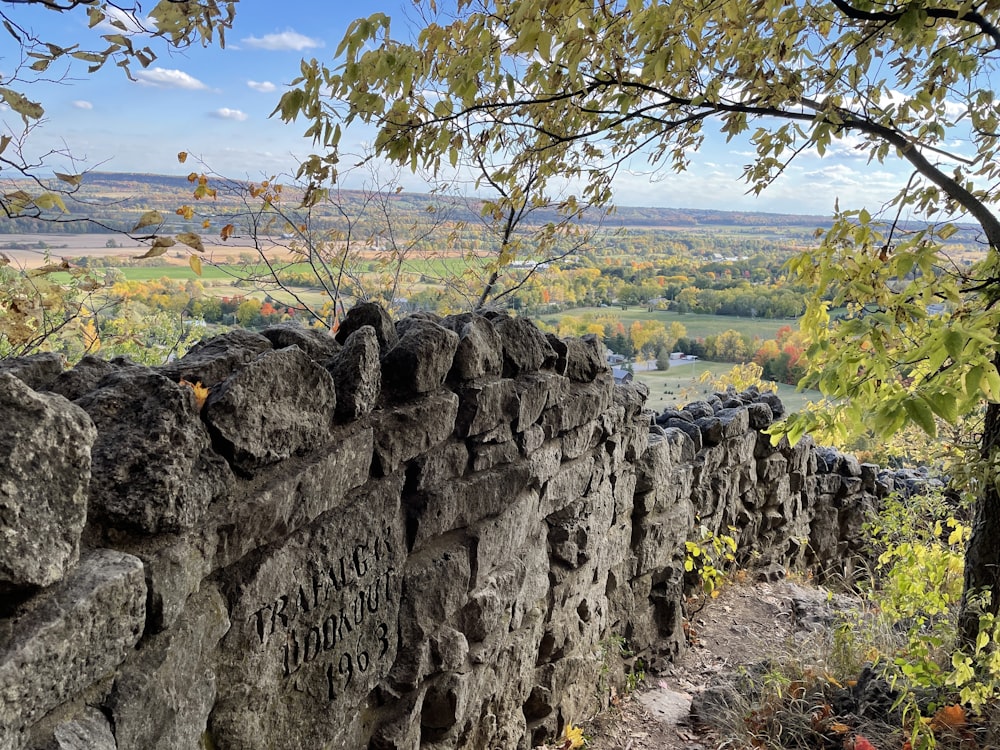 a stone wall with a view of a valley in the distance