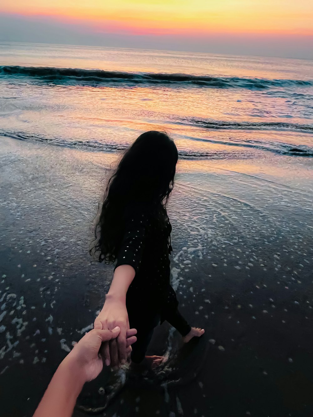 a person holding the hand of another person on a beach