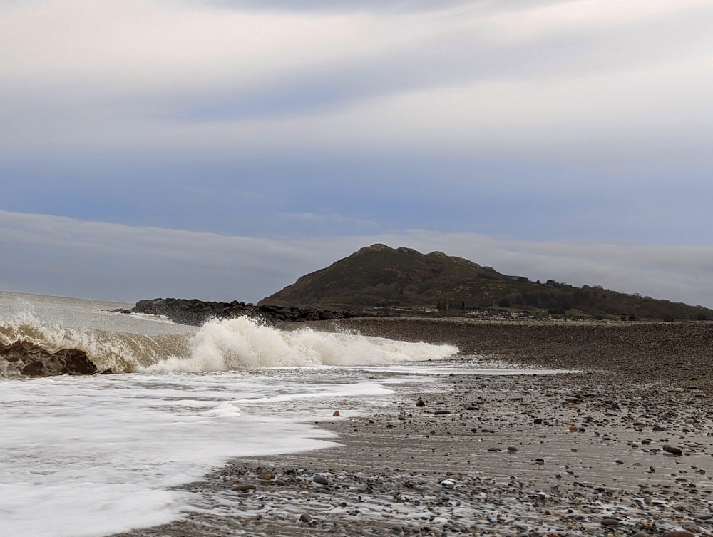 uma grande onda caindo em uma praia rochosa