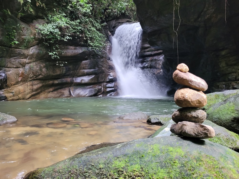 rocks stacked on top of each other in front of a waterfall