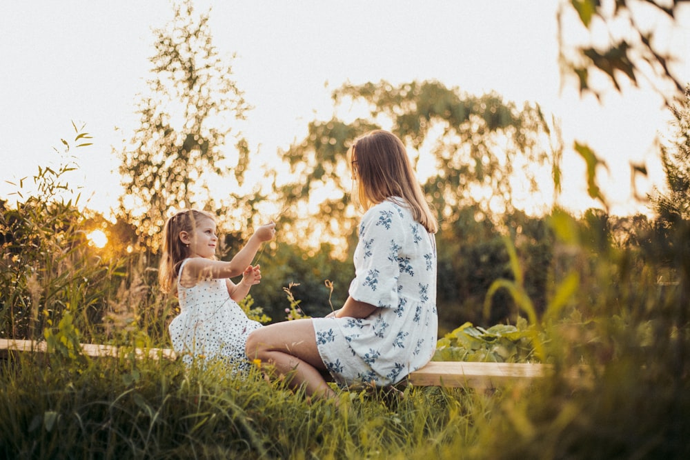 a woman and a little girl sitting on a bench