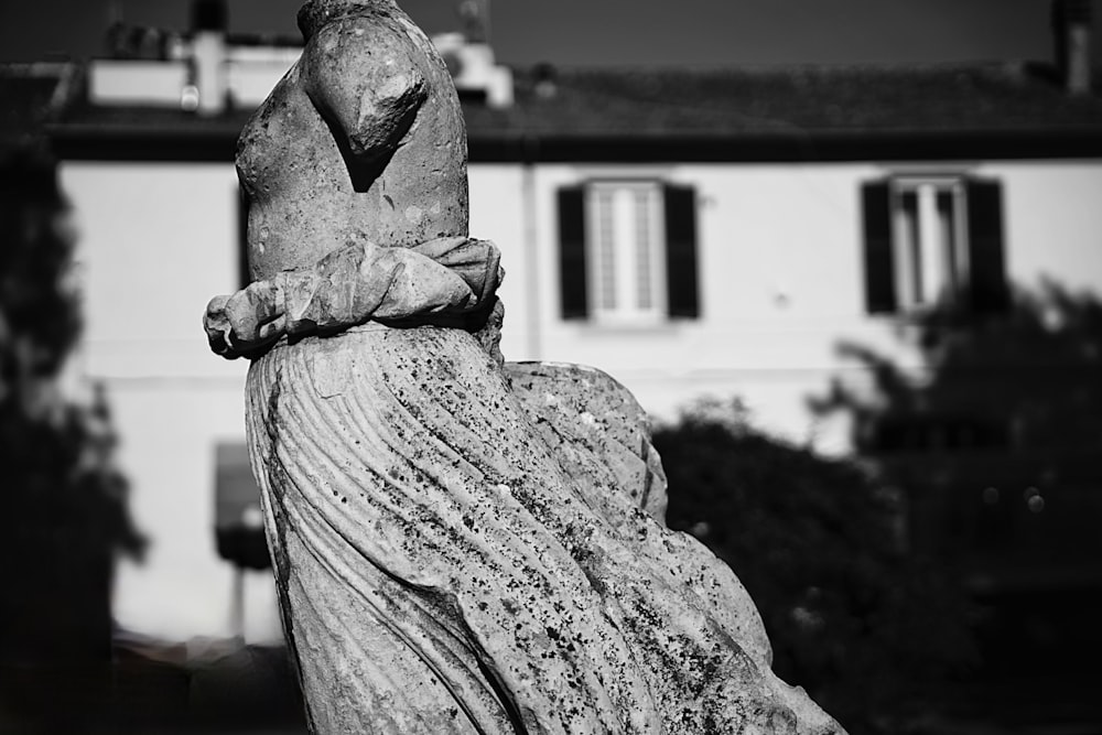 a black and white photo of a statue in front of a house