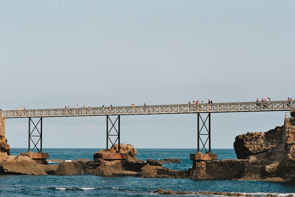 a group of people walking across a bridge over a body of water
