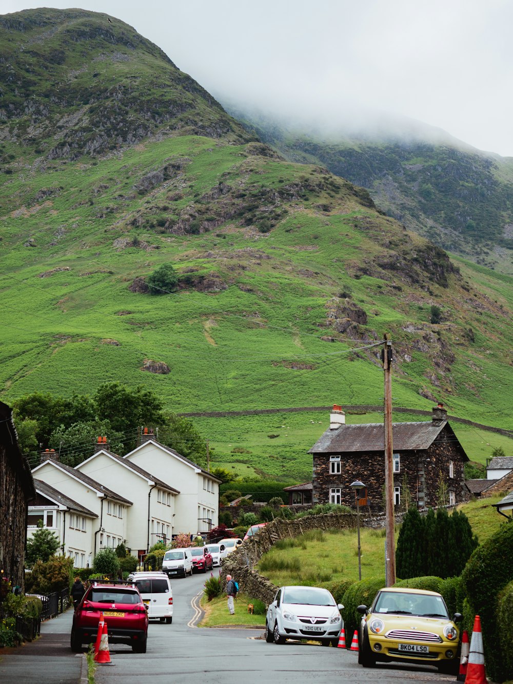 cars parked on the side of a road in front of a mountain