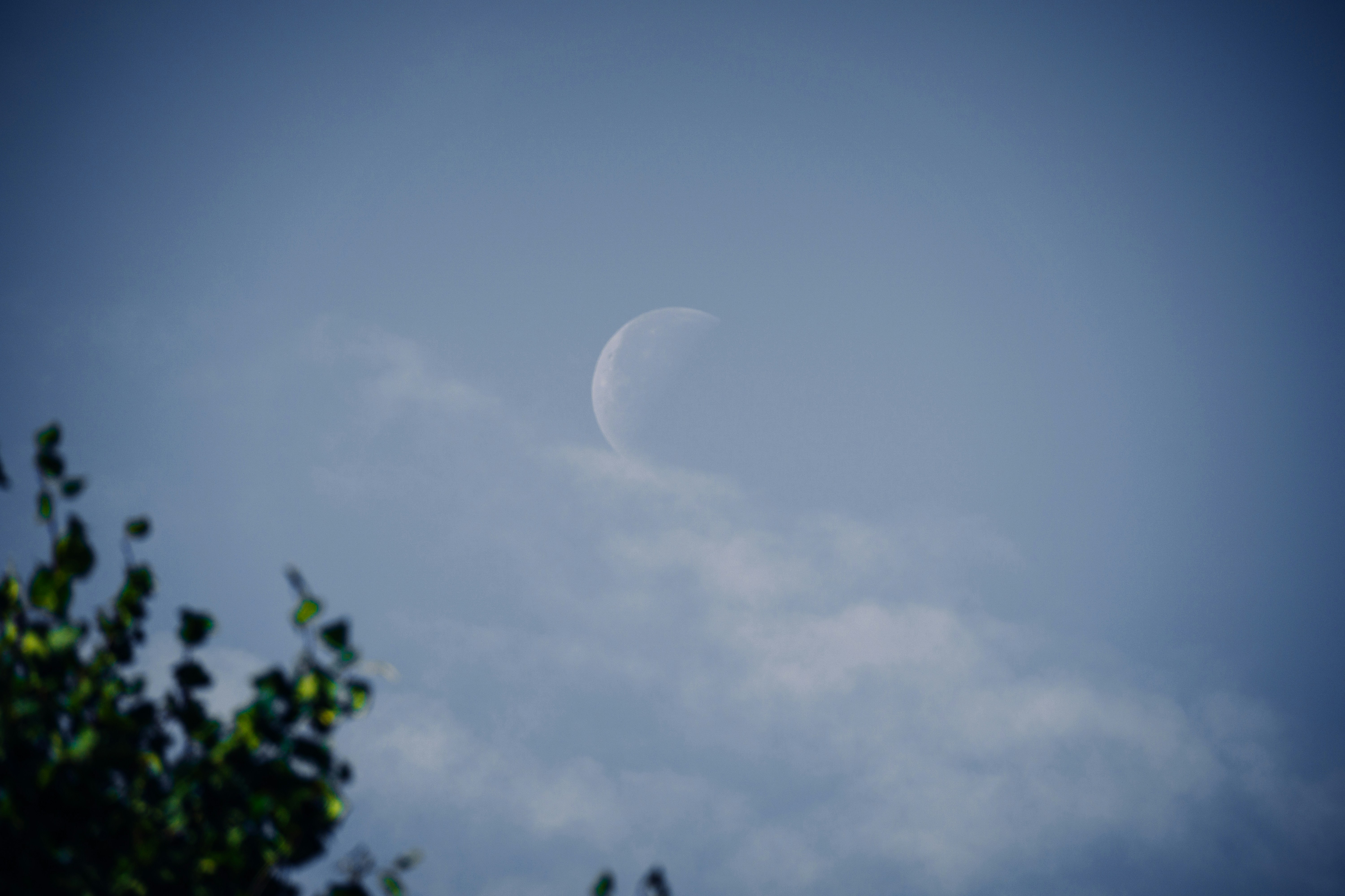 a half moon seen through the clouds in a blue sky