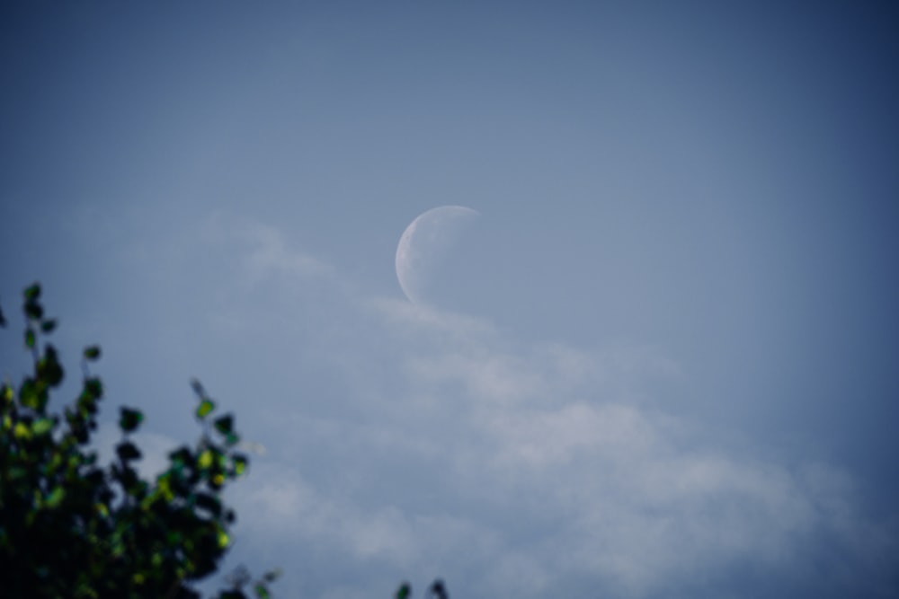 a half moon seen through the clouds in a blue sky