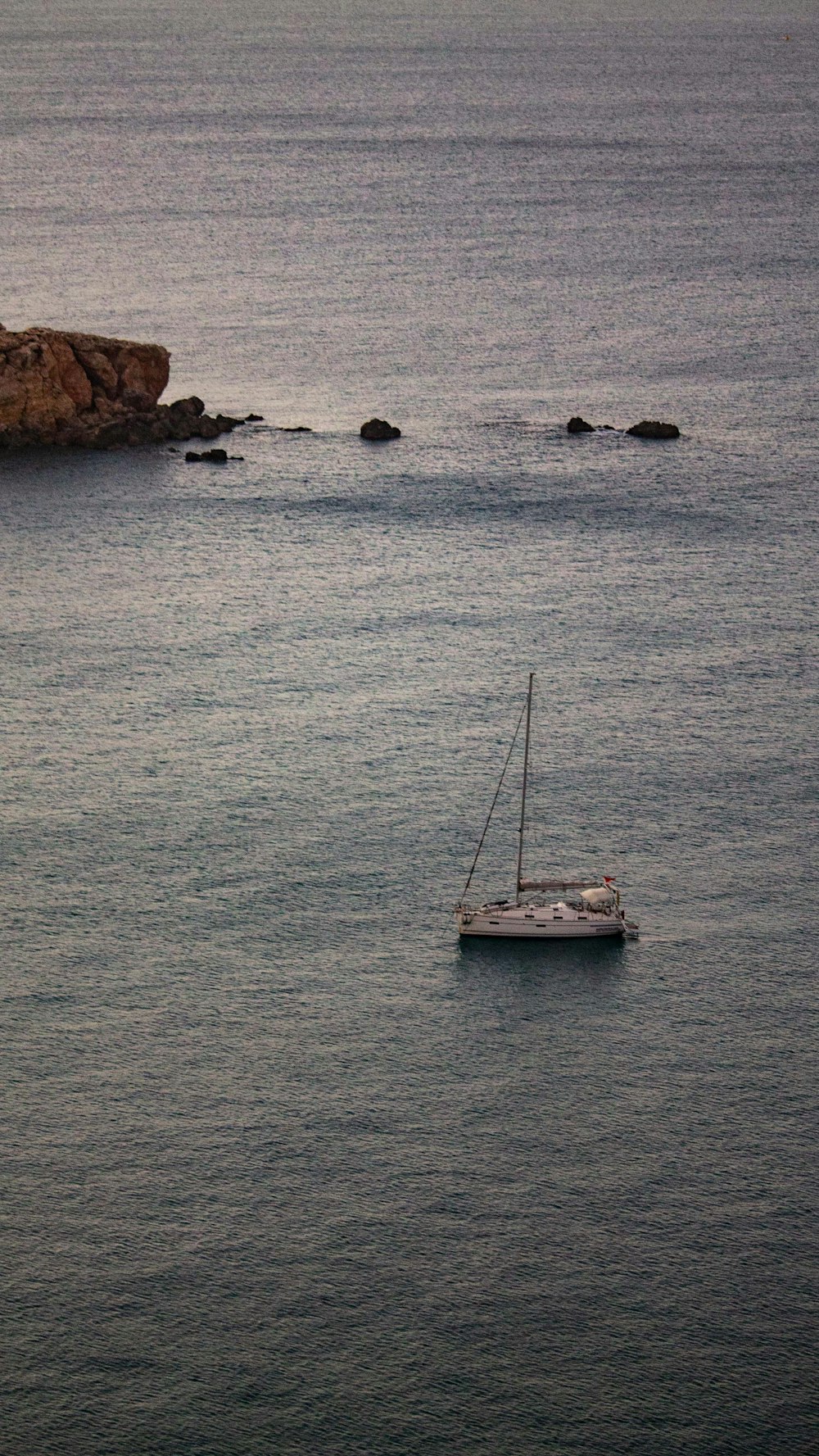 Un velero flotando en el océano cerca de una costa rocosa