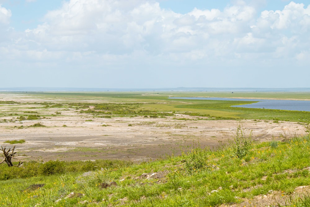 un grande campo aperto con uno specchio d'acqua in lontananza