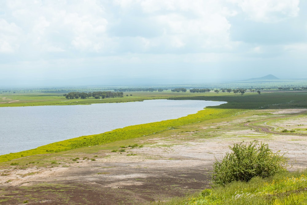 um grande corpo de água sentado ao lado de um campo verde exuberante