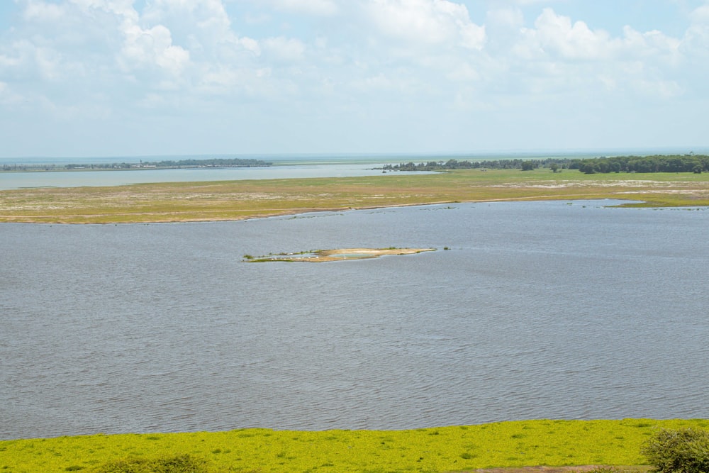 a large body of water surrounded by a lush green field