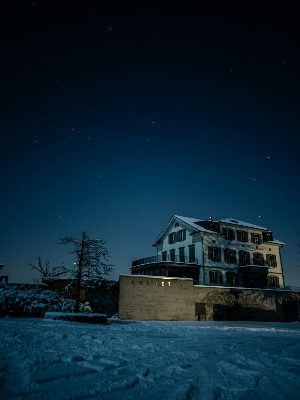una casa en la nieve por la noche con la luna en el cielo