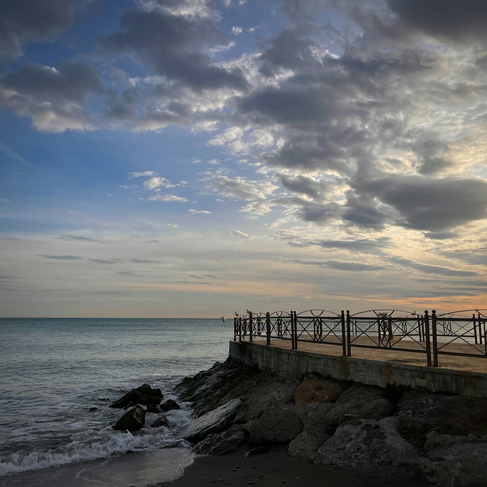 a pier on a rocky shore with the ocean in the background