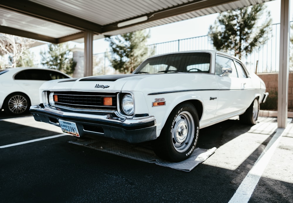 a white car parked in a parking lot next to another car