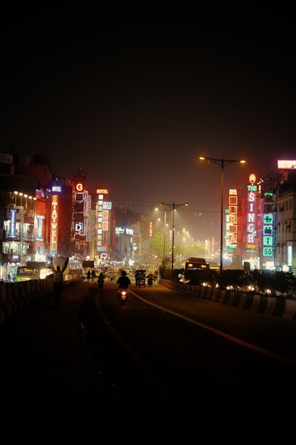 a city street at night with tall buildings lit up