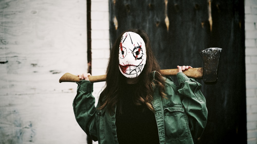 a woman wearing a creepy mask holding a hammer