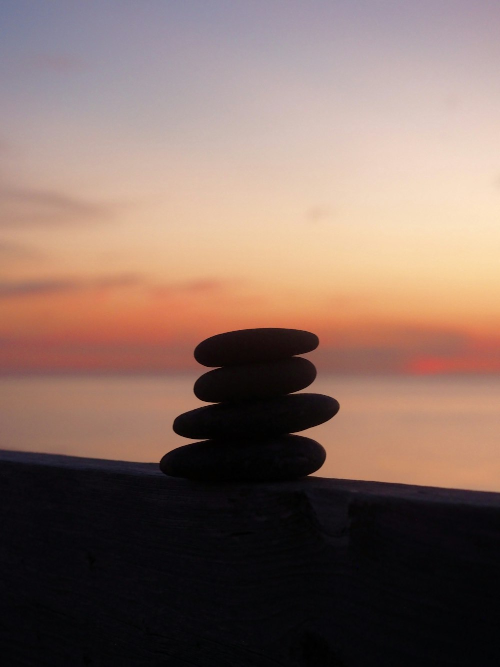 a stack of rocks sitting on top of a wooden fence