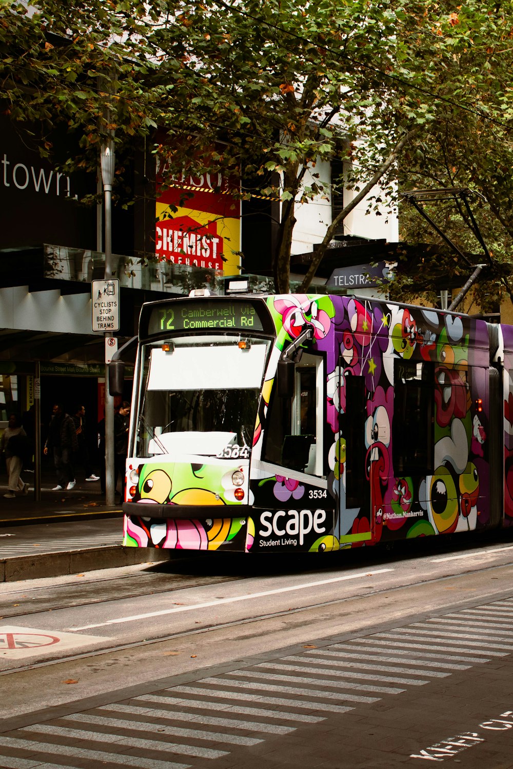 a colorful bus driving down a street next to a tall building