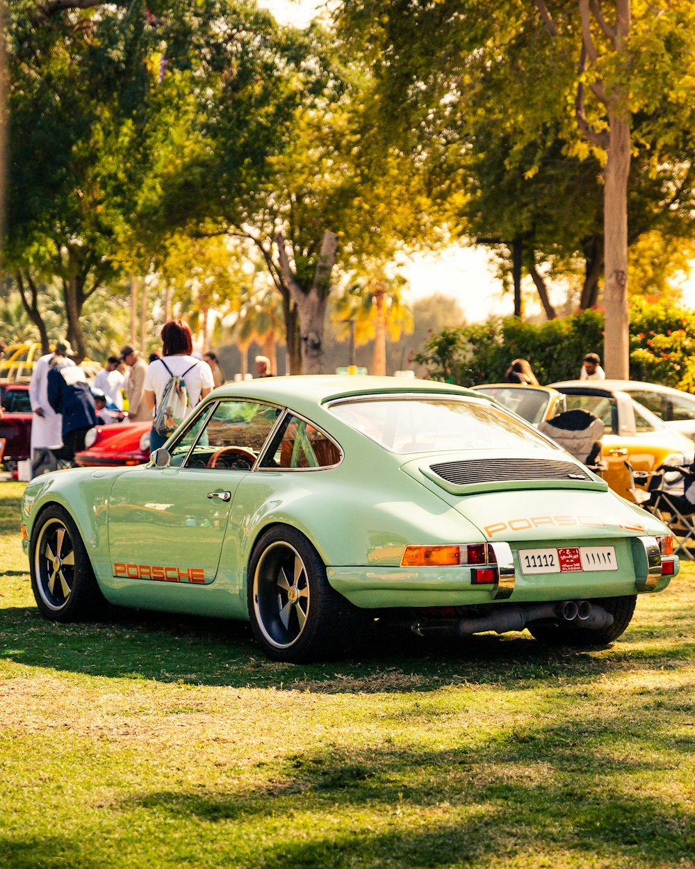 a light green porsche parked in a park