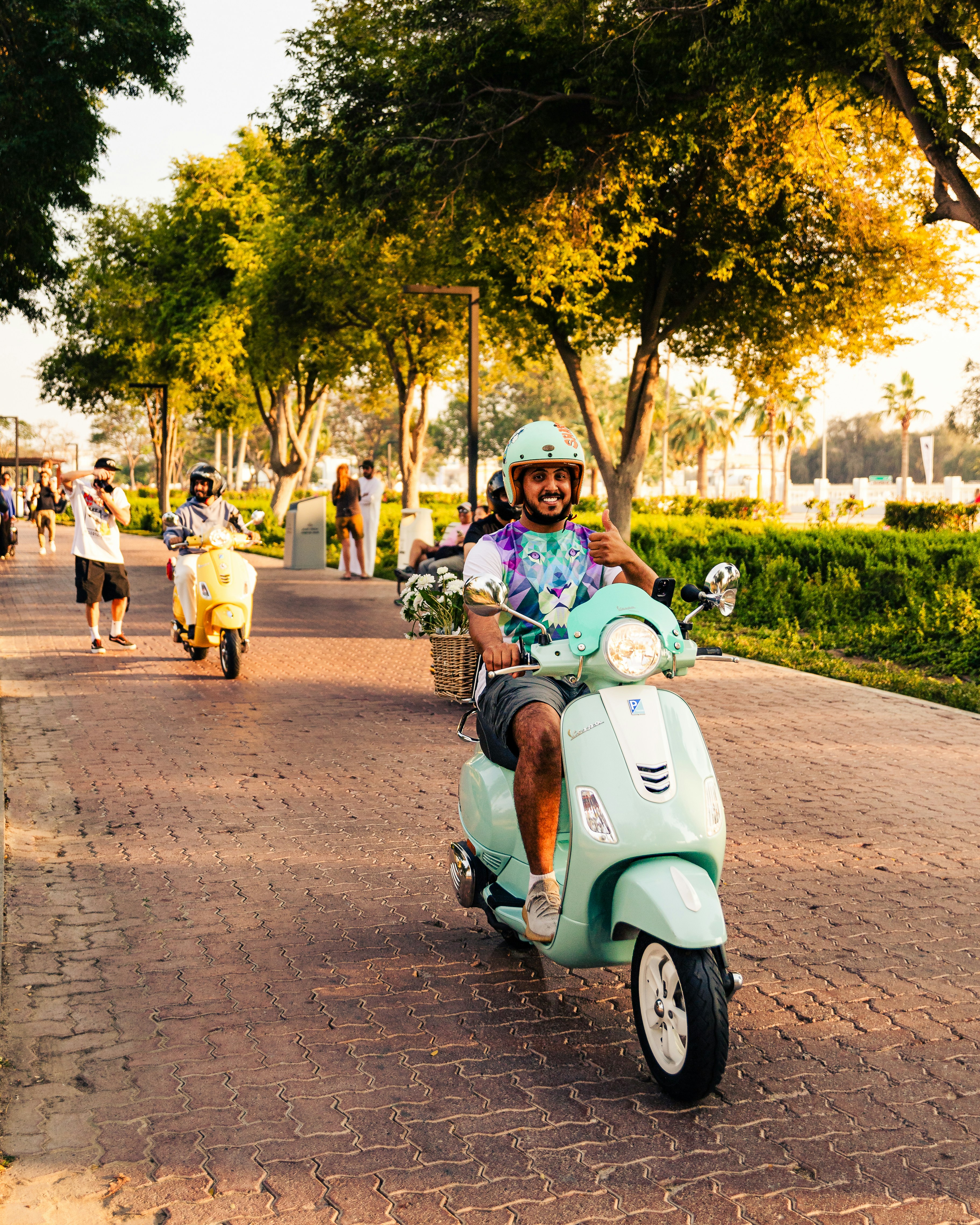 A man riding a scooter down a street photo Free Scooter Image on Unsplash